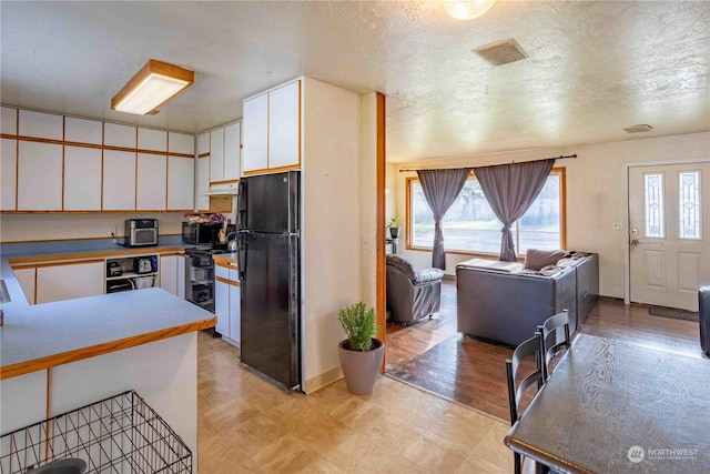 kitchen featuring black appliances, white cabinets, and a textured ceiling