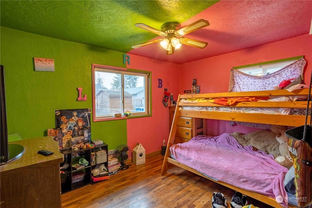 bedroom featuring ceiling fan, wood-type flooring, and a textured ceiling