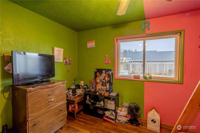 bedroom with ceiling fan, hardwood / wood-style floors, and a textured ceiling