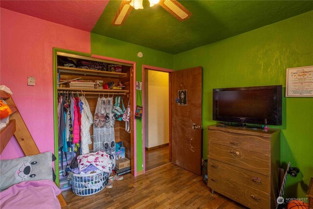 bedroom featuring ceiling fan, a closet, and hardwood / wood-style flooring