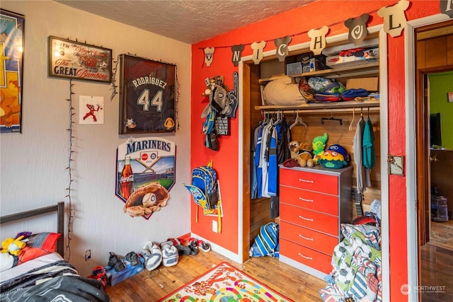 bedroom with a closet, a textured ceiling, and hardwood / wood-style flooring