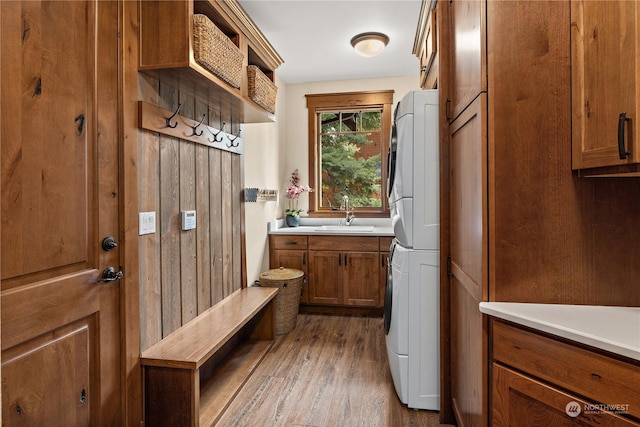 mudroom with sink, stacked washing maching and dryer, and hardwood / wood-style flooring