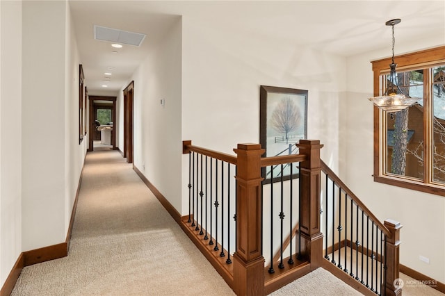 hallway featuring light carpet and an inviting chandelier