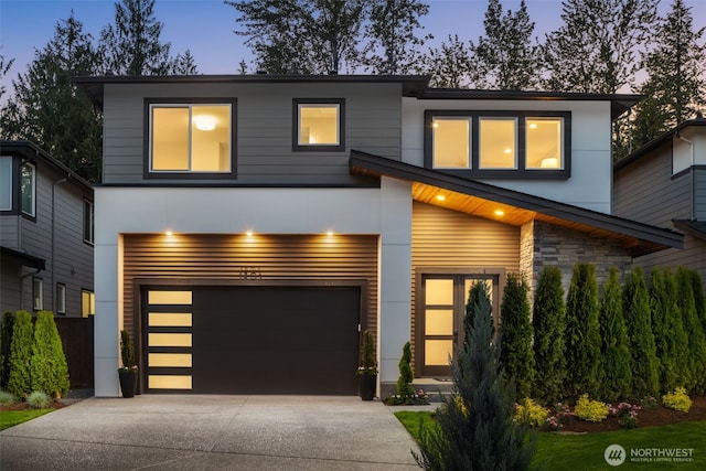 contemporary home featuring a garage, stucco siding, stone siding, and concrete driveway