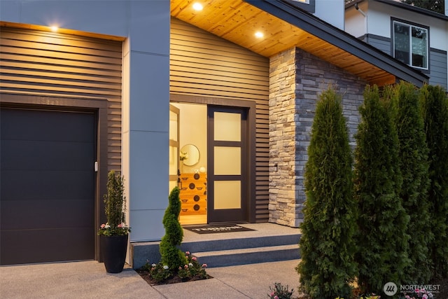 view of exterior entry featuring a garage and stone siding