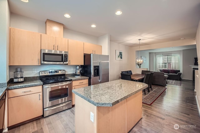 kitchen featuring a kitchen island, appliances with stainless steel finishes, a chandelier, and light brown cabinetry