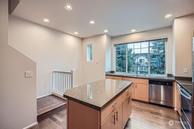 kitchen with sink, light hardwood / wood-style flooring, a kitchen island, stone counters, and stainless steel appliances