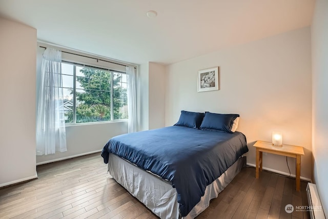 bedroom featuring wood-type flooring and a baseboard heating unit