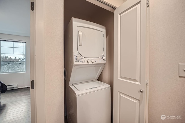 washroom with baseboard heating and stacked washer / dryer