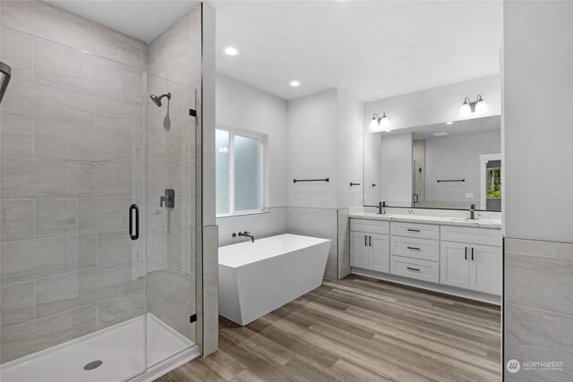 bathroom with hardwood / wood-style floors, vanity, separate shower and tub, and tile walls