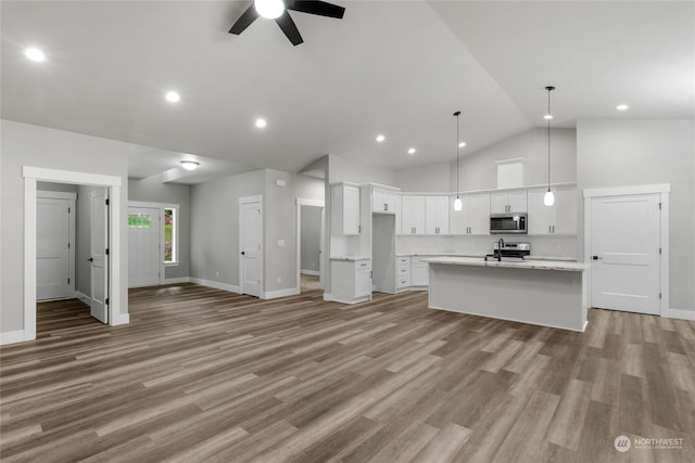 kitchen with a center island with sink, hanging light fixtures, ceiling fan, appliances with stainless steel finishes, and white cabinetry