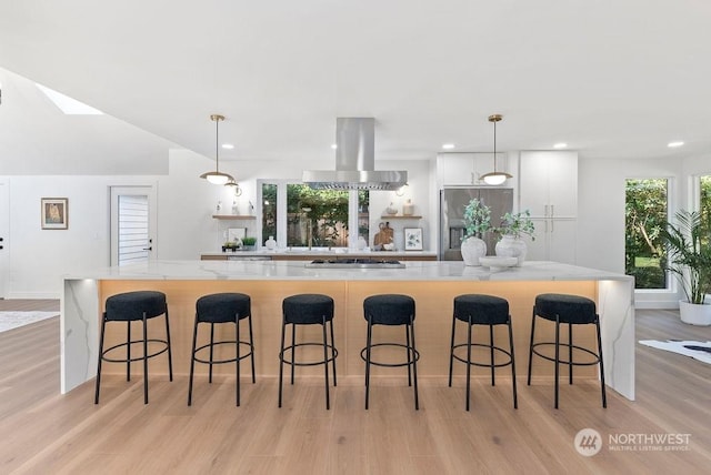 kitchen featuring island exhaust hood, pendant lighting, white cabinetry, and a spacious island