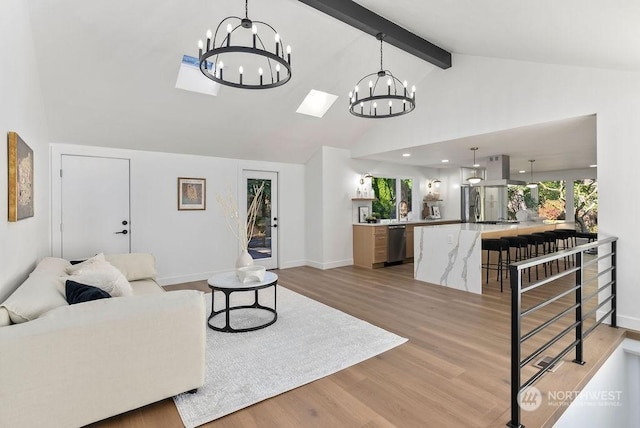 living room featuring a skylight, high vaulted ceiling, beamed ceiling, a chandelier, and light wood-type flooring