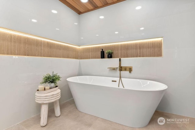 bathroom with wood ceiling, a tub, and tile walls