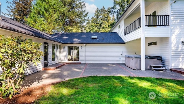 back of house with a yard, a balcony, a patio, and a hot tub