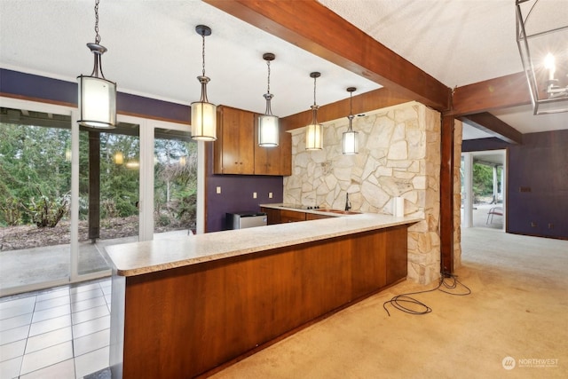 kitchen with plenty of natural light, pendant lighting, beam ceiling, and kitchen peninsula