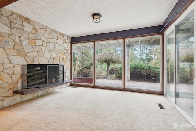 unfurnished living room with carpet floors and a stone fireplace