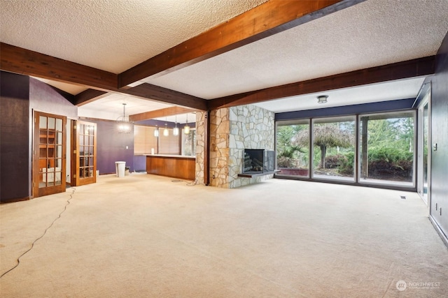 unfurnished living room featuring carpet floors, a textured ceiling, beamed ceiling, and a fireplace