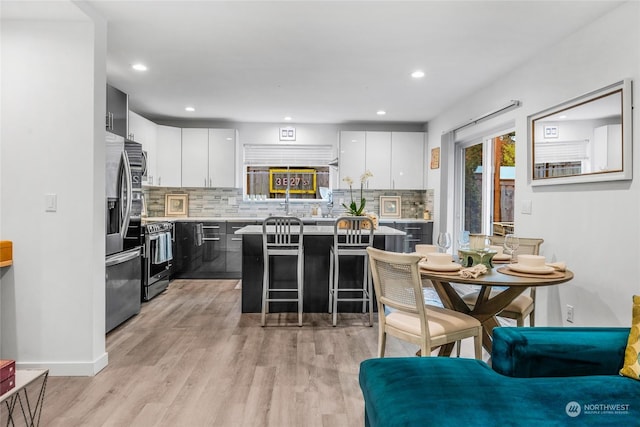 kitchen with backsplash, white cabinetry, a breakfast bar, and appliances with stainless steel finishes