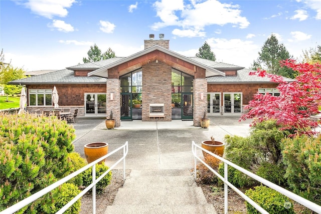 rear view of house featuring a patio area, a fireplace, and french doors