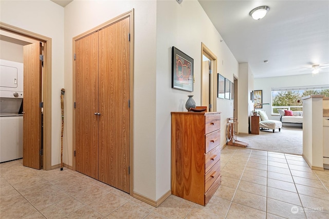 hallway featuring light colored carpet and stacked washer and clothes dryer