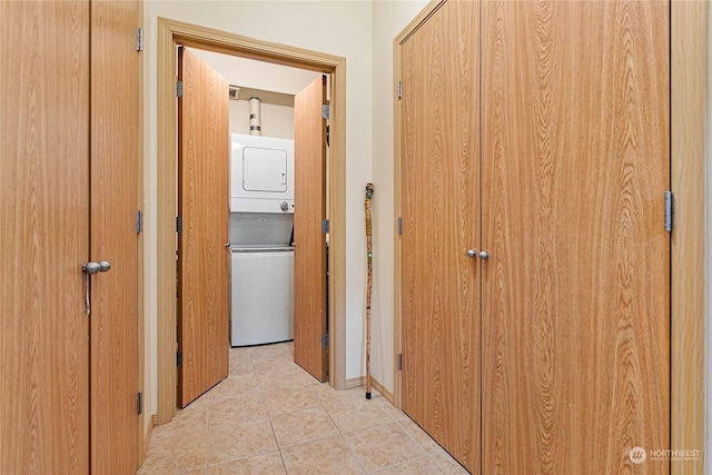 corridor featuring stacked washer / dryer and light tile patterned floors