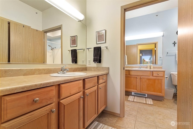 bathroom featuring tile patterned flooring, a shower, vanity, and toilet