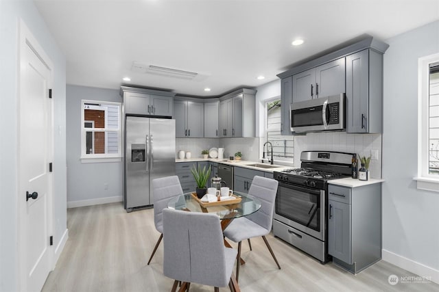 kitchen featuring light hardwood / wood-style floors, stainless steel appliances, gray cabinets, and sink