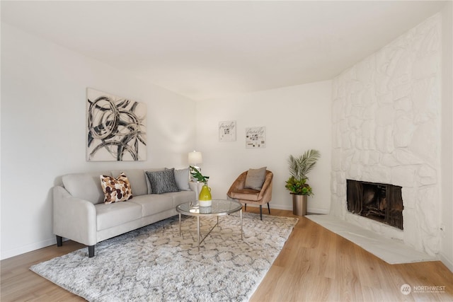 living room with hardwood / wood-style flooring and a stone fireplace