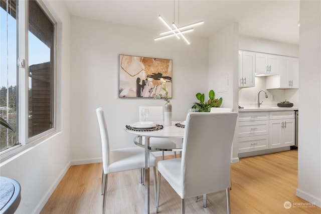 dining area with a chandelier, sink, and light hardwood / wood-style flooring