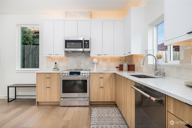 kitchen featuring white cabinets, sink, light hardwood / wood-style flooring, appliances with stainless steel finishes, and plenty of natural light