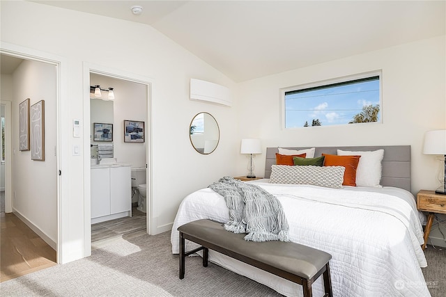 bedroom with light wood-type flooring, connected bathroom, and lofted ceiling