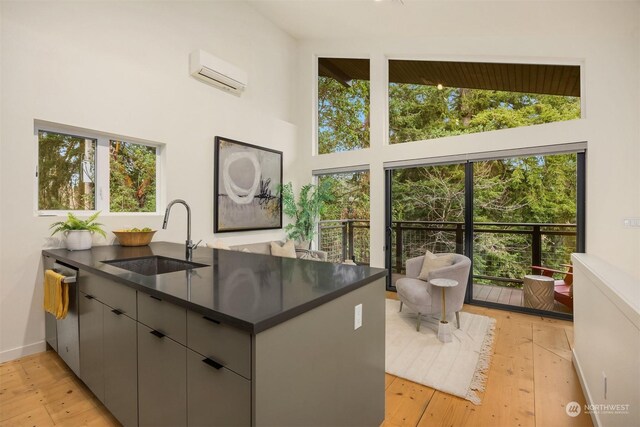 kitchen featuring sink, a wall mounted air conditioner, plenty of natural light, light hardwood / wood-style floors, and gray cabinets