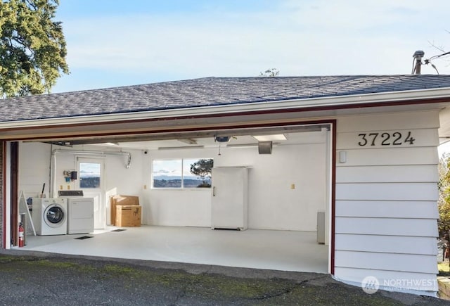 garage with washing machine and dryer and a garage door opener