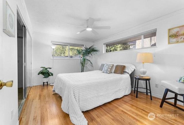 bedroom featuring ceiling fan, a closet, crown molding, and wood-type flooring