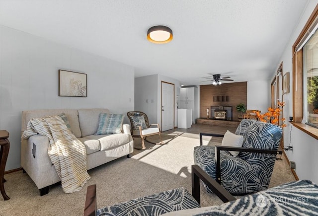 carpeted living room featuring ceiling fan and a large fireplace