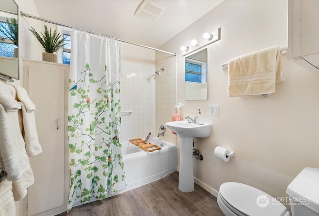 full bathroom with sink, hardwood / wood-style floors, shower / bathtub combination with curtain, and toilet