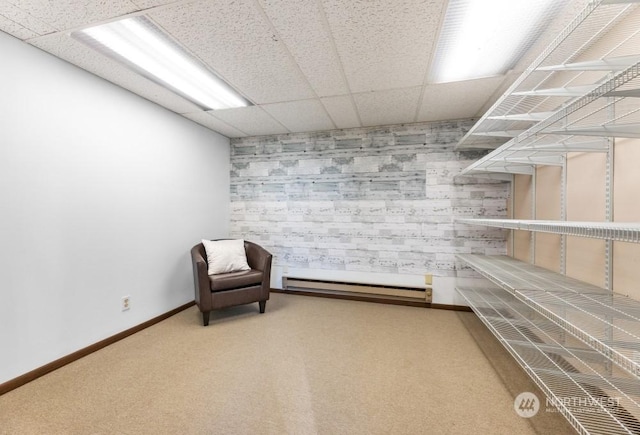 interior space with carpet, a drop ceiling, and a baseboard heating unit