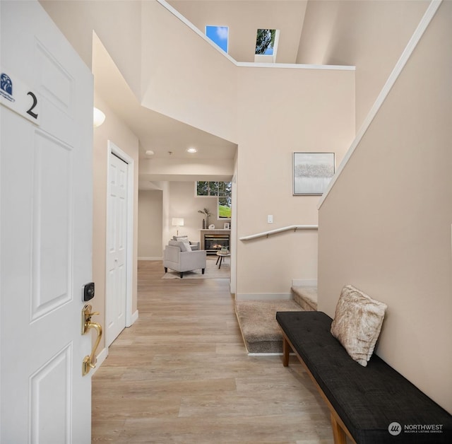 hallway with light wood-type flooring and a high ceiling