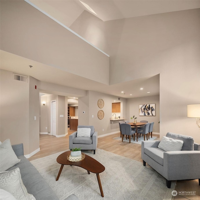 living room with a towering ceiling and light wood-type flooring