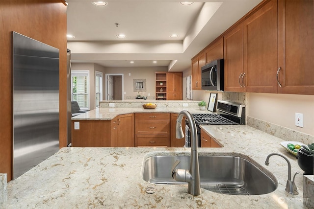 kitchen with kitchen peninsula, light stone countertops, sink, and stainless steel appliances