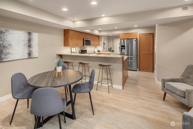 dining area with a tray ceiling and light hardwood / wood-style flooring