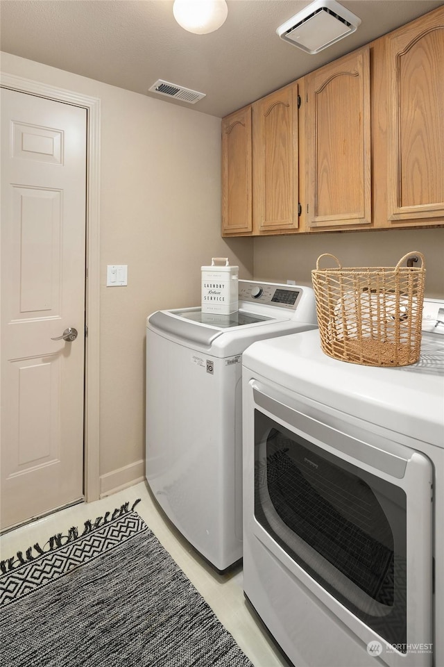 clothes washing area featuring cabinets and independent washer and dryer