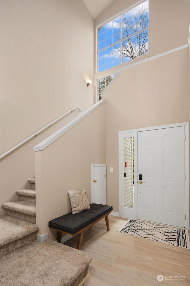 entrance foyer with a towering ceiling and light hardwood / wood-style floors