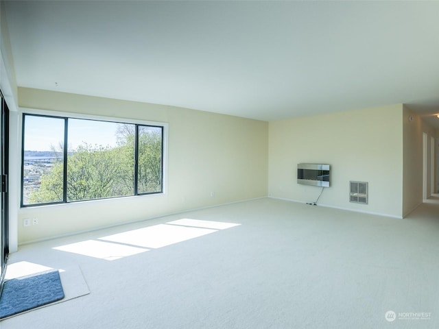 spare room featuring light carpet and heating unit