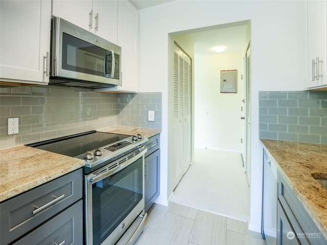 kitchen with light carpet, appliances with stainless steel finishes, backsplash, light stone counters, and white cabinetry