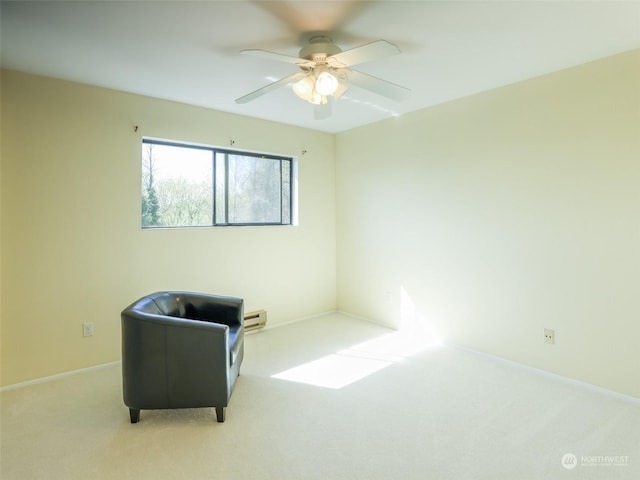 living area featuring ceiling fan, light colored carpet, and a baseboard heating unit