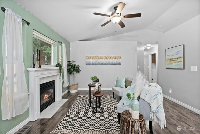 living room featuring ceiling fan, a tile fireplace, lofted ceiling, and dark hardwood / wood-style floors