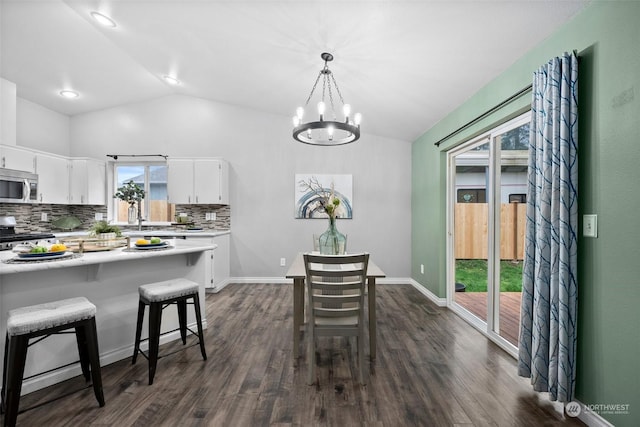 dining room with sink, dark hardwood / wood-style flooring, lofted ceiling, and a chandelier