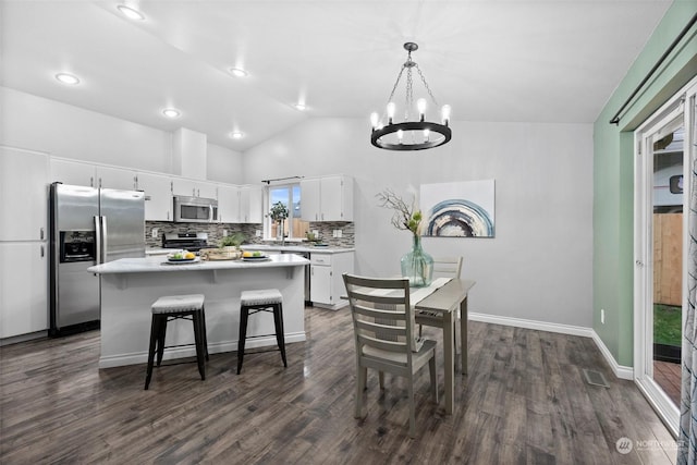 kitchen featuring decorative light fixtures, white cabinets, lofted ceiling, a chandelier, and appliances with stainless steel finishes